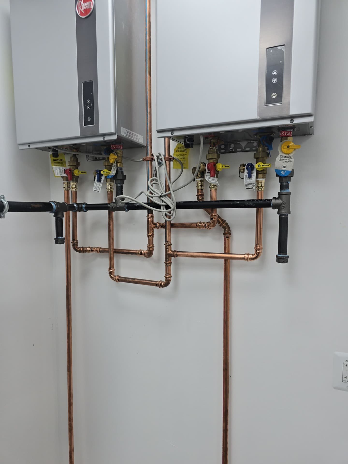 Twin tankless water heaters with copper piping and gas-shutoff manifold installed by Will's Plumbing